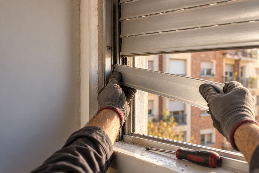Manos de un técnico encajando una lama de aluminio en la guía de una persiana