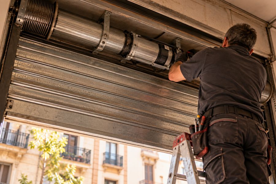 Técnico en una escalera revisando el motor central de un cierre metálico